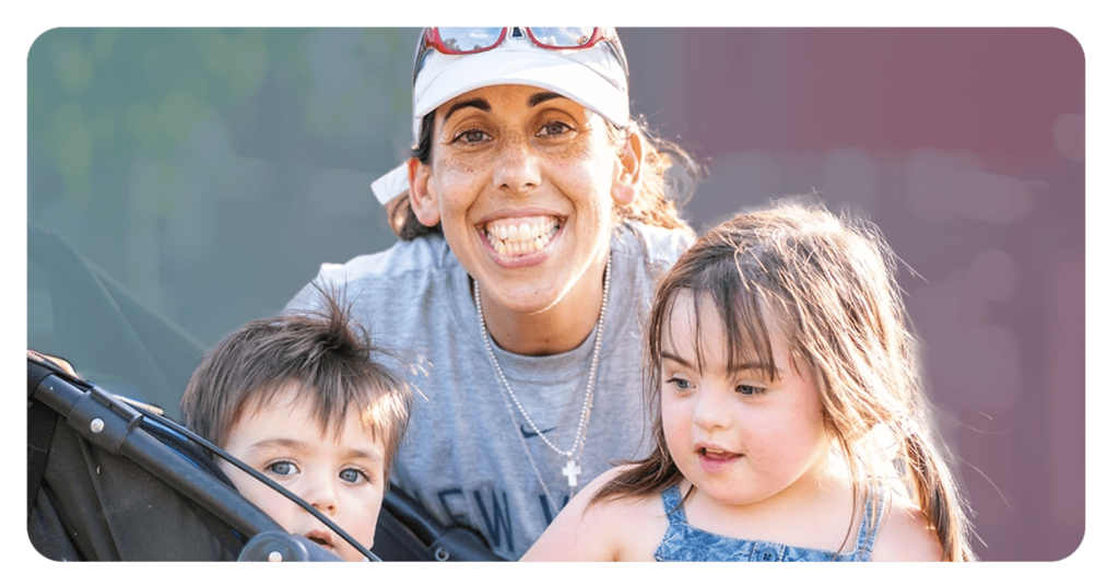 A mother and her two children smiling as they enjoy a sunny day